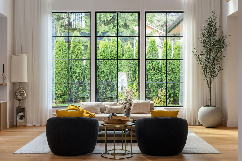 Luxury living room with modern decor, featuring floor-to-ceiling windows showcasing natural light and highlighting sleek, minimalist furniture against a neutral palette.