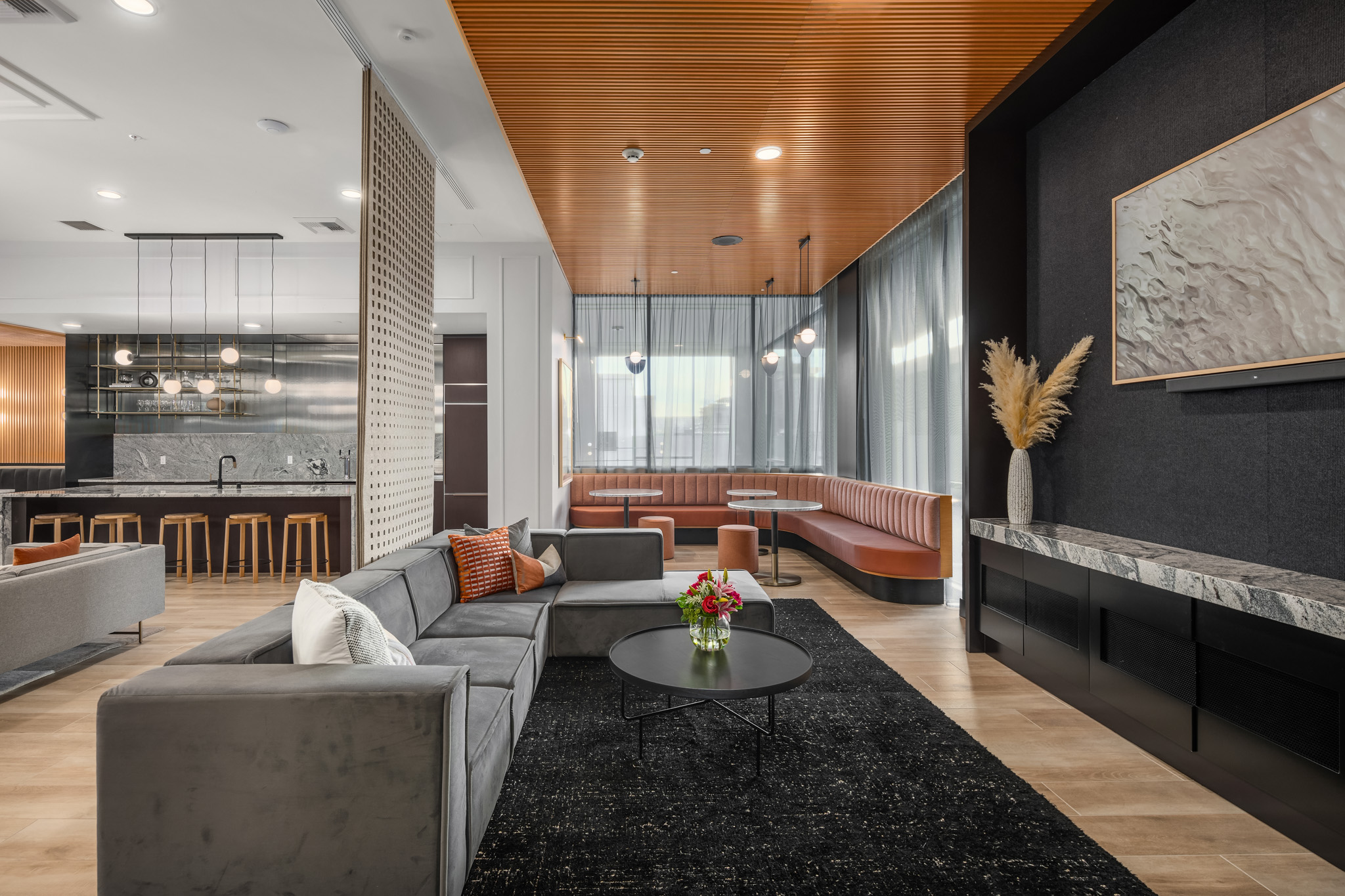 Modern living room with stylish gray sectional sofa, elegant round coffee table, and warm wood accents. Features a cozy dining nook with curved seating and large windows, creating an inviting atmosphere in a Pacific Northwest high-rise.