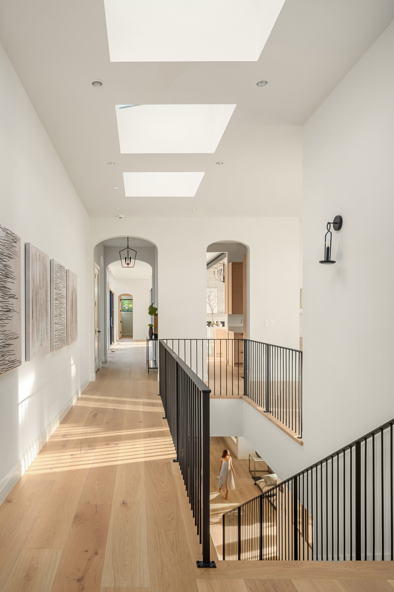 Bright and airy modern hallway featuring skylights and elegant black railings, showcasing contemporary design elements in a Pacific Northwest home.
