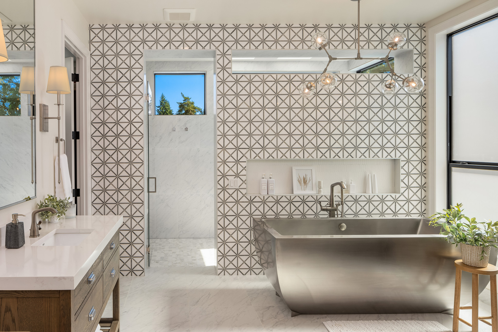 Modern bathroom with sleek stainless steel bathtub, geometric patterned tile walls, and large windows providing natural light, located in the Pacific Northwest.