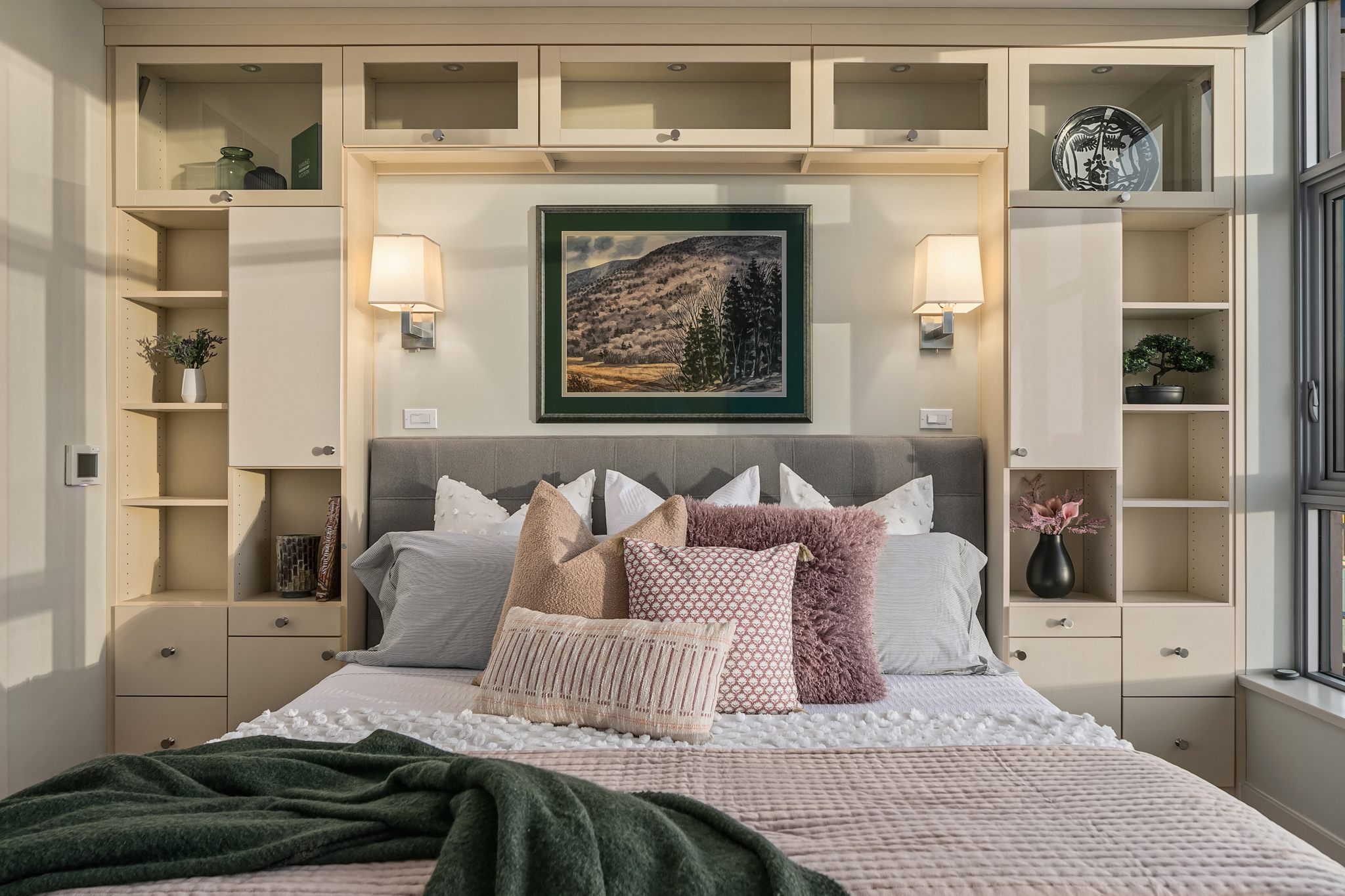 Cozy bedroom with modern design featuring a plush bed adorned with decorative pillows, built-in shelving, and soft lighting, located in Seattle, Washington.
