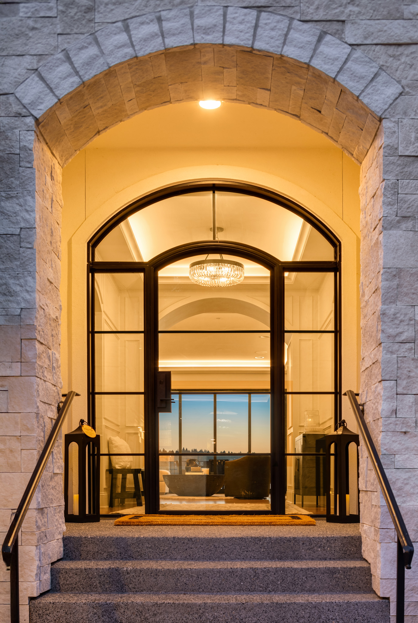 Elegant entrance of a modern home featuring a grand arched doorway and stylish chandelier, set against a twilight backdrop in the Pacific Northwest.