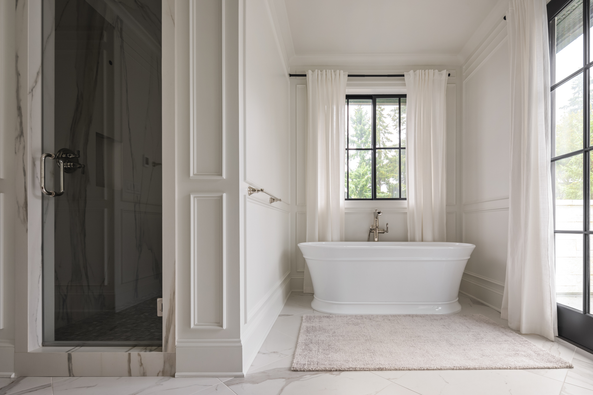 Elegant bathroom featuring a freestanding bathtub, modern fixtures, and large windows with sheer curtains, located in the Pacific Northwest.