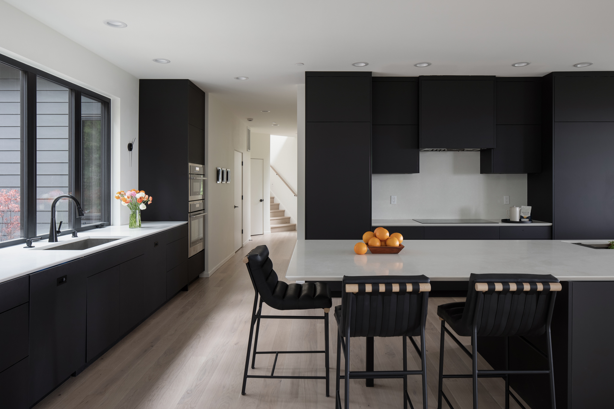 Modern kitchen featuring sleek black cabinetry, a large island with a light countertop, and stylish bar stools, located in the Pacific Northwest.