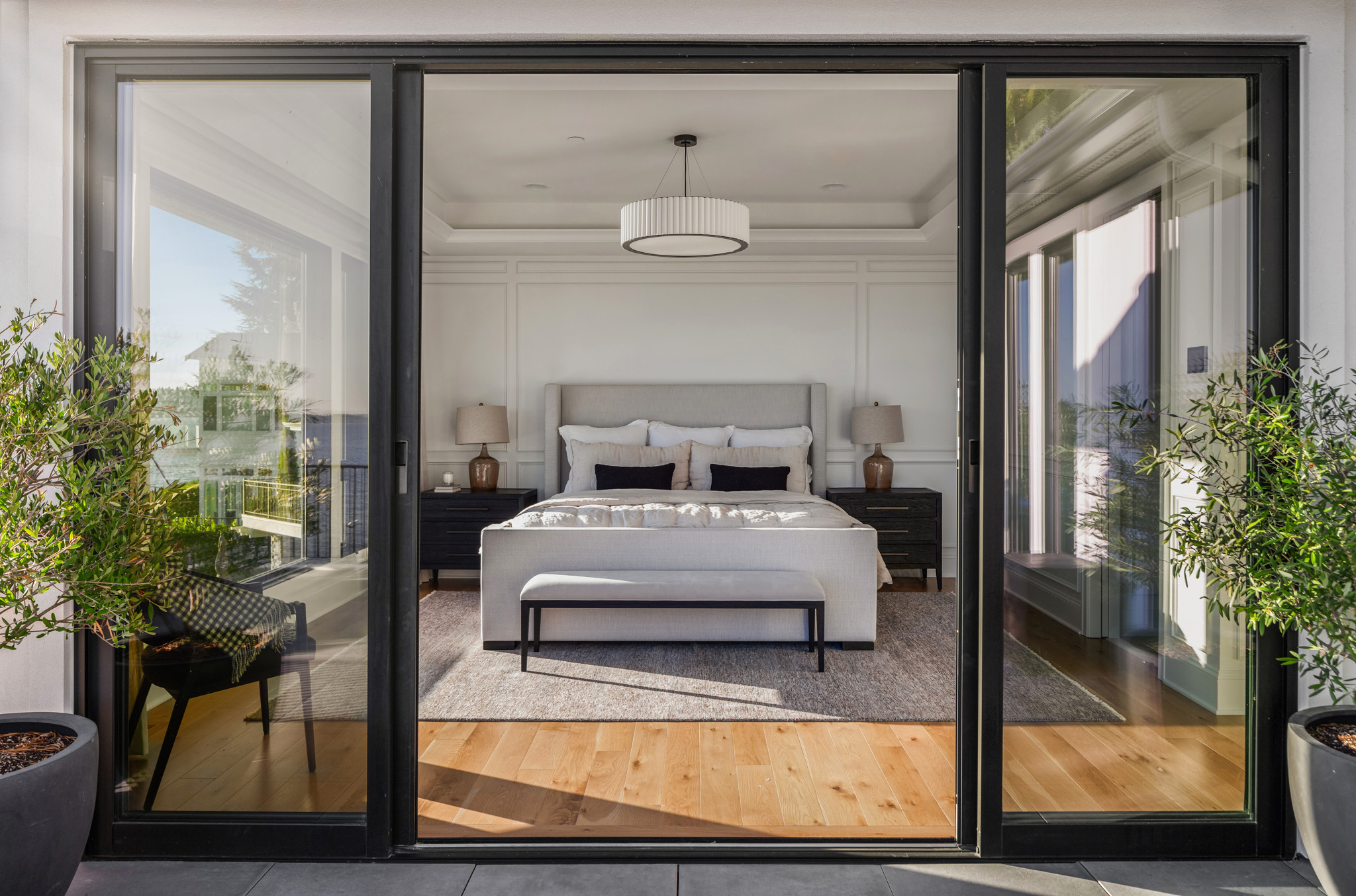 Modern bedroom with elegant furnishings, featuring a plush bed, stylish lamps, and hardwood flooring, showcasing a serene view in the Pacific Northwest.