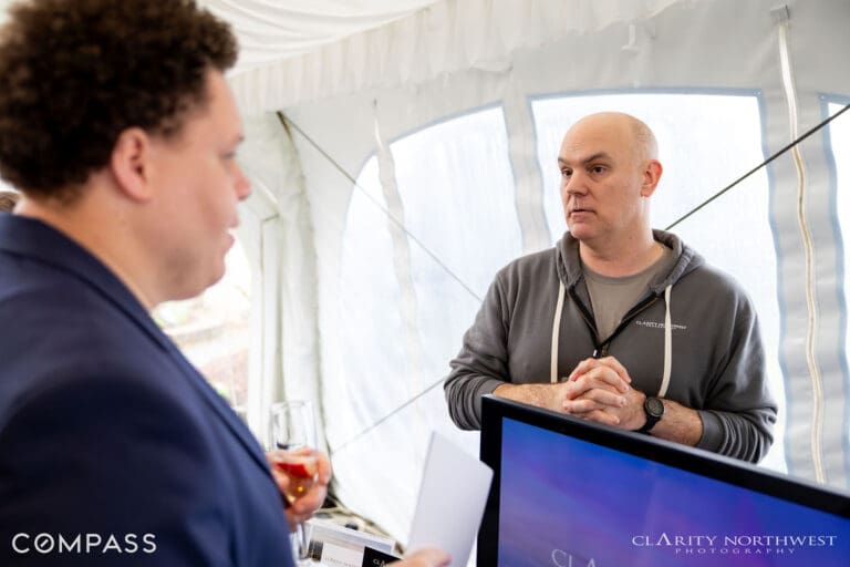 Networking event featuring two professionals engaged in conversation under a tent in the Pacific Northwest, showcasing a relaxed atmosphere perfect for real estate discussions.
