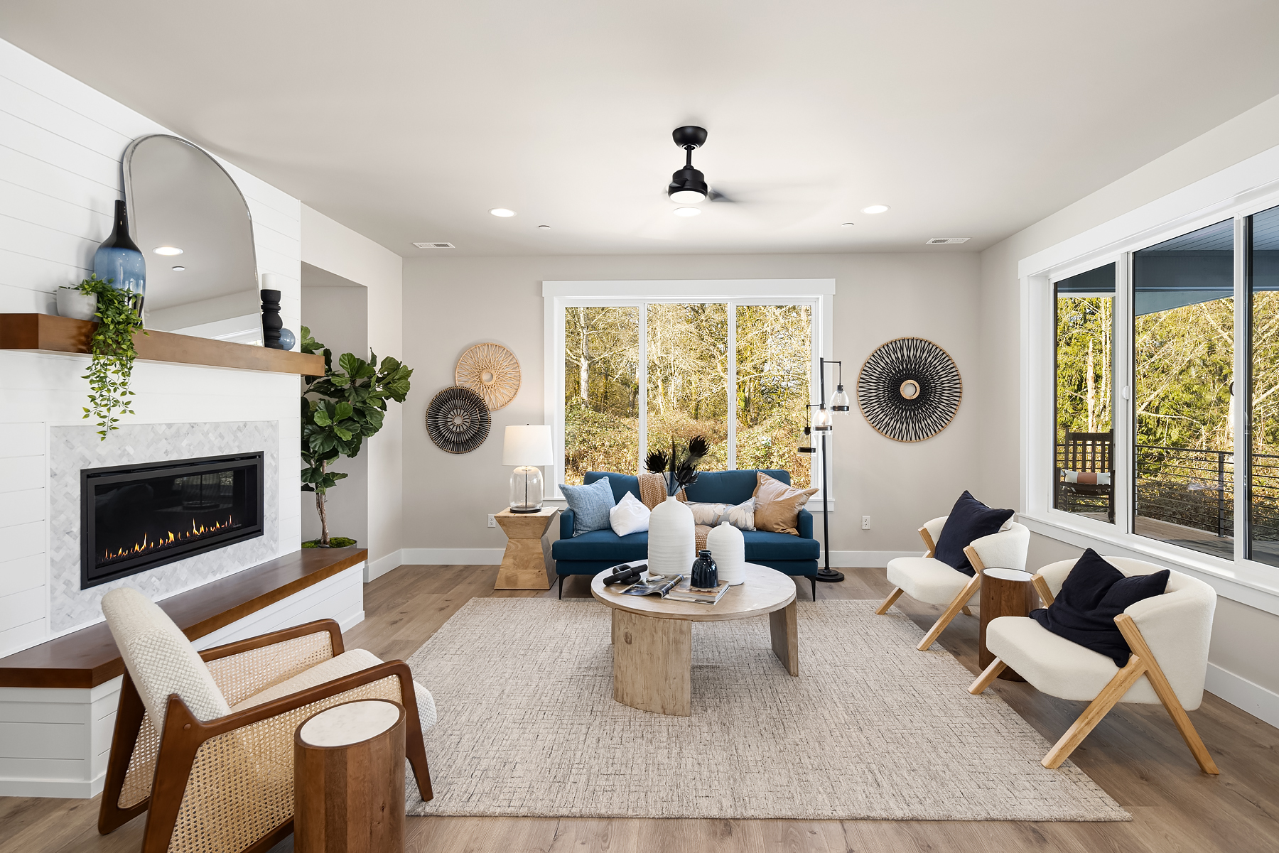 Modern living room featuring a cozy fireplace, stylish furniture, and large windows with views of greenery, located in the Pacific Northwest.