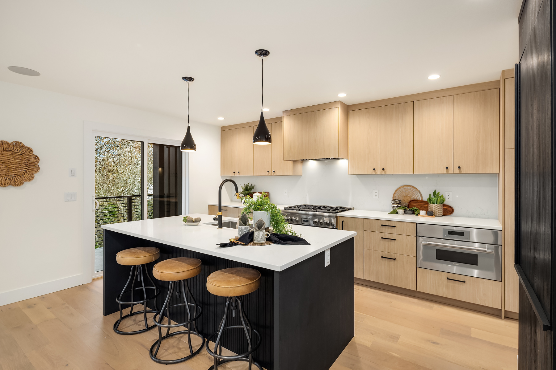 Modern kitchen featuring light wood cabinetry, sleek appliances, and a spacious island with bar seating, located in the Pacific Northwest.
