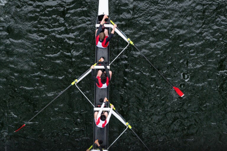 Rowers in synchronized motion on dark waters, showcasing teamwork and athleticism in a vibrant and competitive atmosphere, set in the Pacific Northwest.