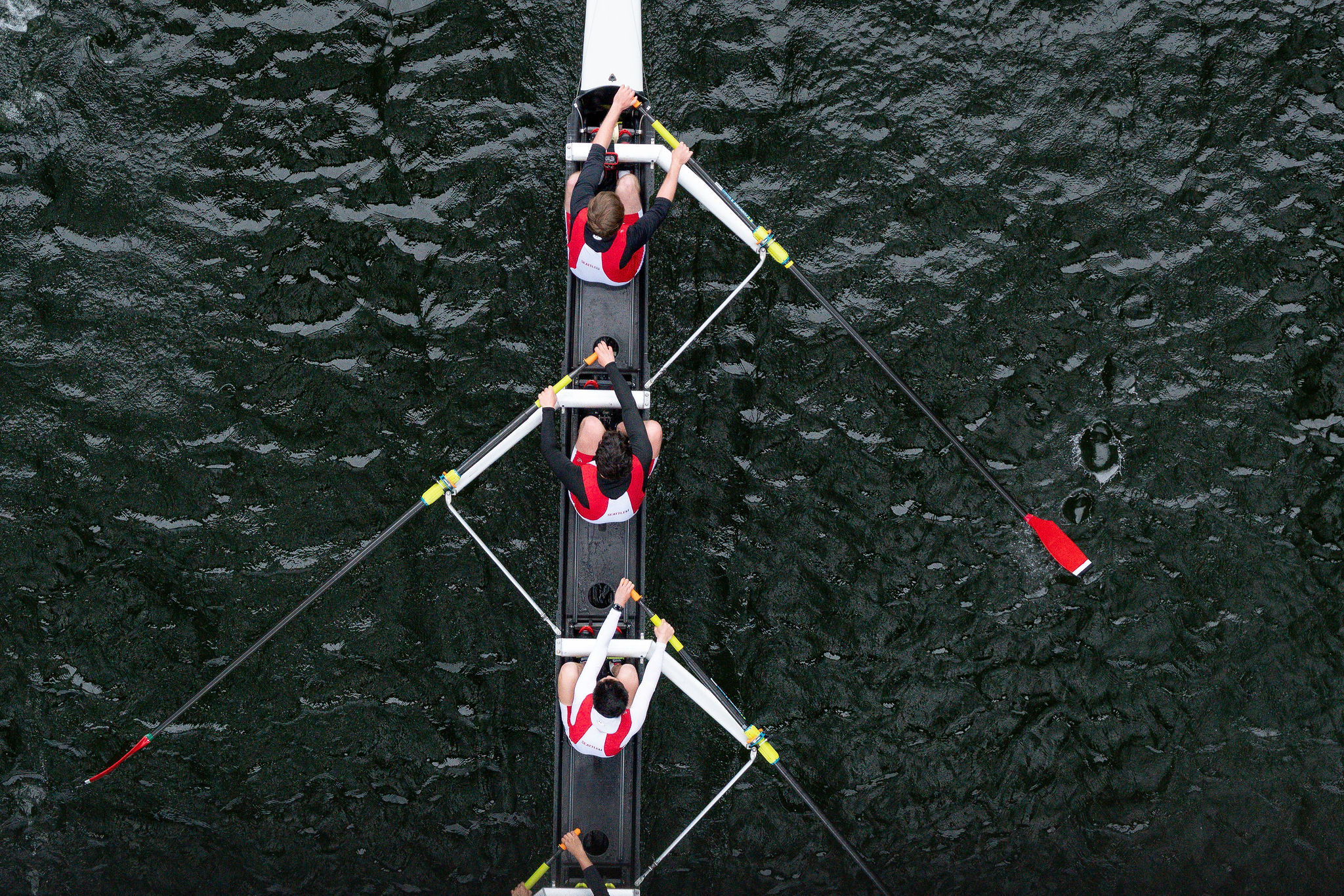 Rowers in synchronized motion on dark waters, showcasing teamwork and athleticism in a vibrant and competitive atmosphere, set in the Pacific Northwest.