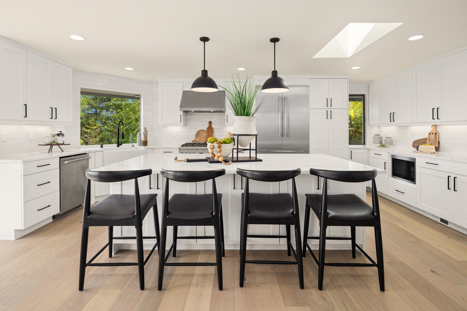 Modern kitchen with white cabinetry, sleek black accents, and a spacious island featuring bar seating, located in the Pacific Northwest.